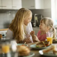 Mother and daughter eating breakfast together in the kitchen.
